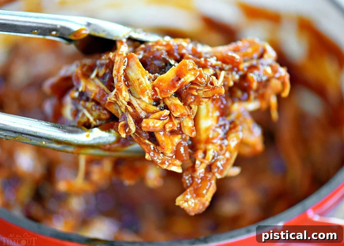 Juicy BBQ pulled chicken held by tongs above a saucepan, highlighting its tender texture and rich sauce.
