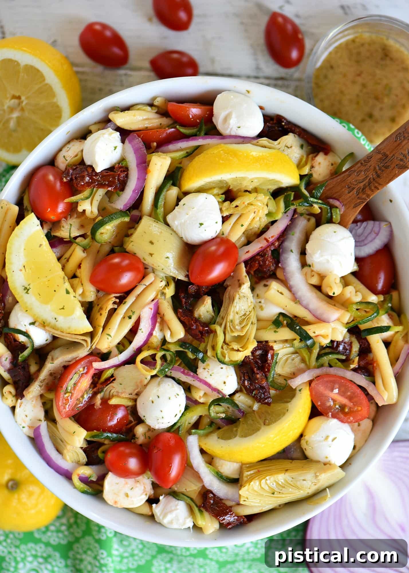 The ultimate Zucchini Pasta Salad recipe for summer. Featuring spiralized zucchini, sun-dried tomatoes, fresh mozzarella, artichokes, and a light vinaigrette dressing. Perfect for a healthy, delicious, and easy meal. A large bowl of Zucchini Pasta Salad with Sun-Dried Tomatoes, Mozzarella, and Artichokes, beautifully garnished and ready to serve, with a recipe card nearby.