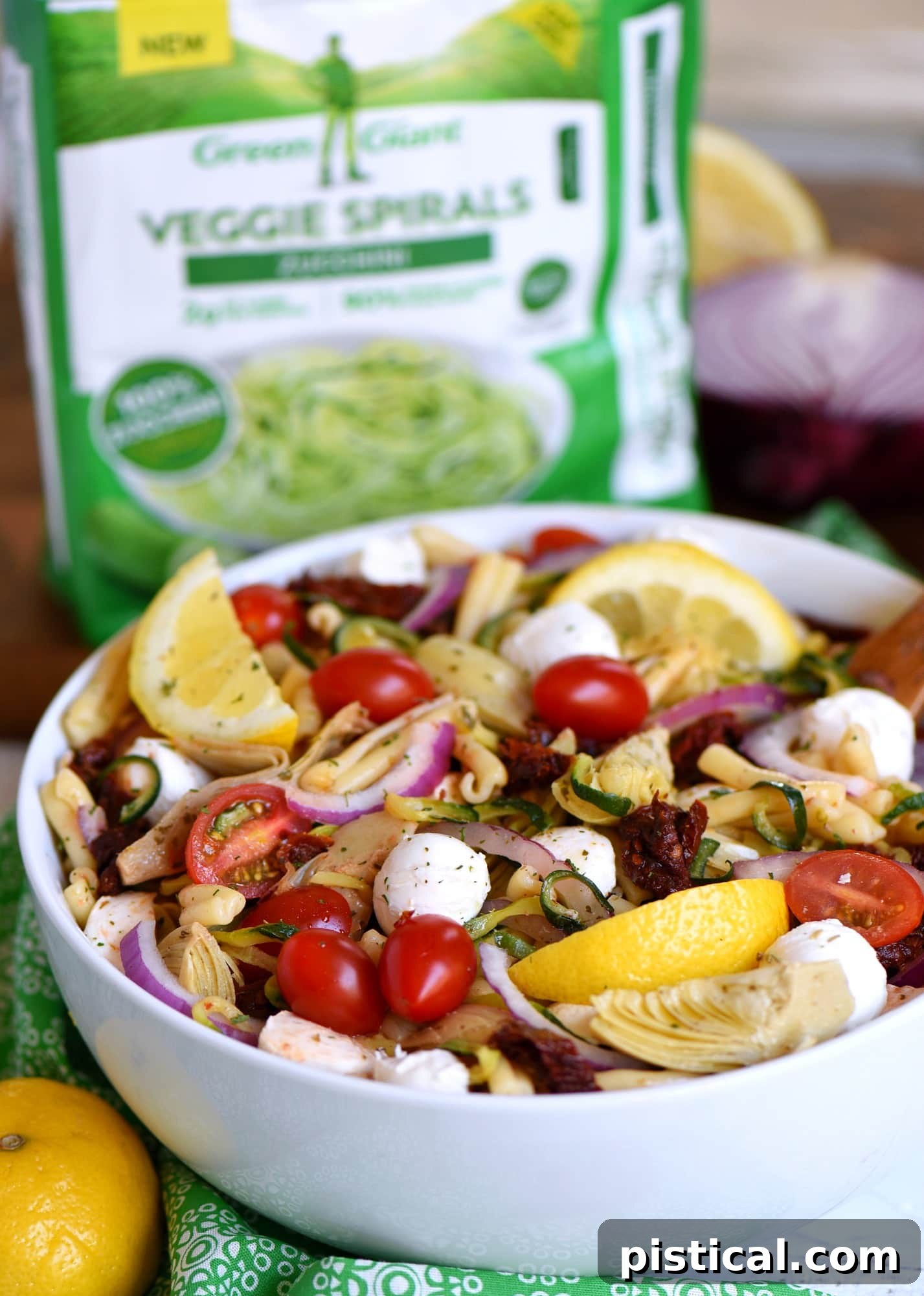 The perfect summer Zucchini Pasta Salad, boasting a medley of colors and flavors from zucchini, pasta, sun-dried tomatoes, and mozzarella, dressed in a zesty vinaigrette. A beautifully presented bowl of Zucchini Pasta Salad with Sun-Dried Tomatoes and Mozzarella on a rustic wooden table, ready for a summer meal.