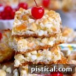 A vibrant close-up of a Piña Colada Magic Bar with a cherry on top, showcasing the layers of tropical goodness.
