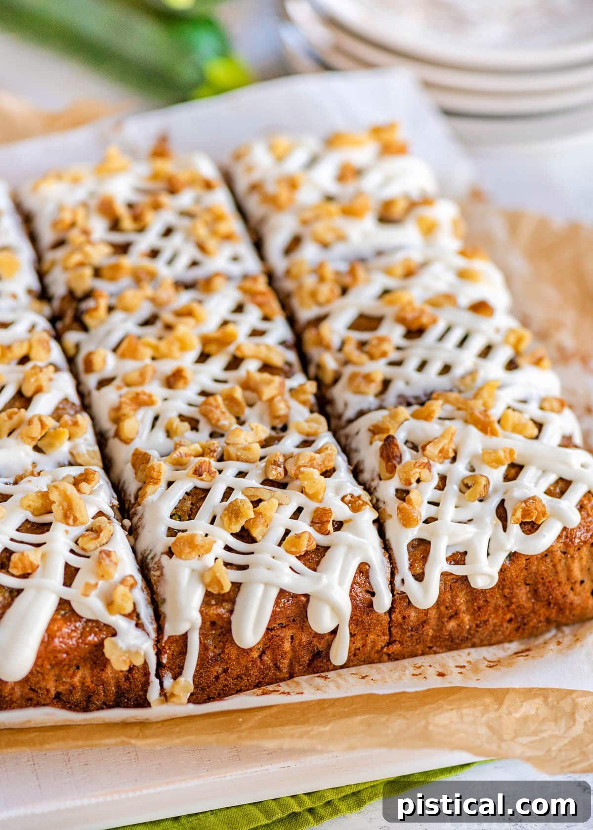 A freshly baked zucchini snack cake, cut into nine perfect squares and arranged on parchment paper on a white cutting board.