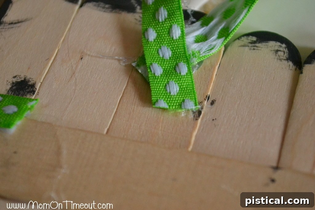 Step-by-step guide: Gluing a ribbon loop to the back of the craft stick snowman for hanging as an ornament or door hanger.