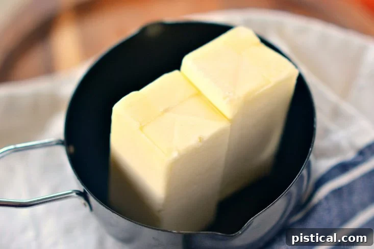 Unsalted butter melting in a saucepan on low heat.