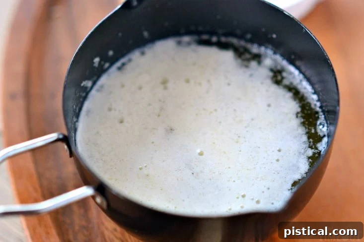 Foamy milk solids rising to the surface of melting butter.