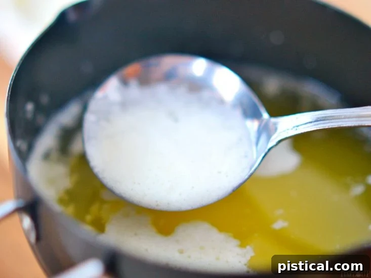 Skimming the white foam from the surface of clarifying butter.