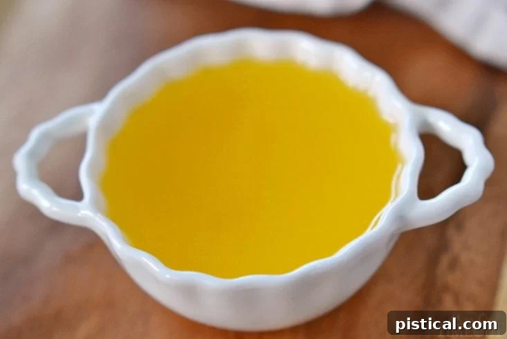 Freshly made clarified butter cooling in a glass jar, displaying its bright golden color.
