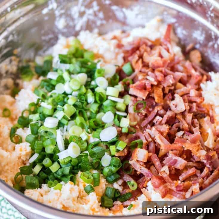Fresh ingredients for the best twice baked potatoes: a blend of dairy, cheese, bacon, and potatoes for a truly gourmet side. From Mom On Timeout. Various ingredients for twice baked potatoes laid out in bowls, including russet potatoes, olive oil, sour cream, cream cheese, butter, shredded cheddar cheese, green onions, and crumbled bacon, ready for preparation.
