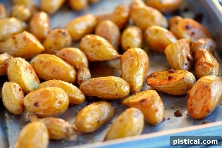 Close-up of golden and crispy quick garlic roasted potatoes on a baking sheet, fresh out of the oven