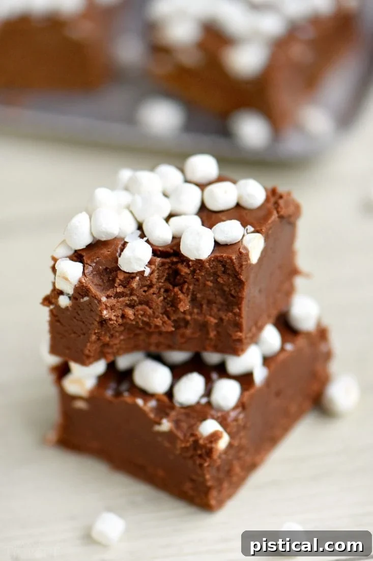 Easy Hot Cocoa Fudge Recipe A batch of freshly made hot cocoa fudge, with one square partially removed, showing the creamy interior.