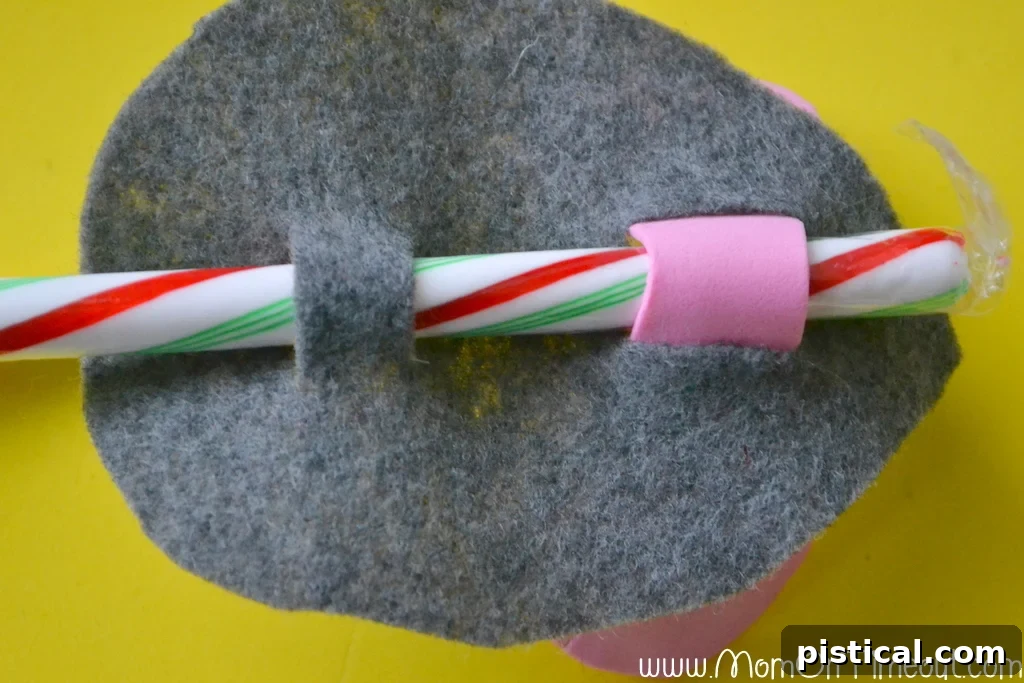 Candy Cane Christmas Mice Craft Step 6 Step-by-step instructions for Candy Cane Christmas Mice: Underside view showing how the candy cane is secured through ear slits for stability.