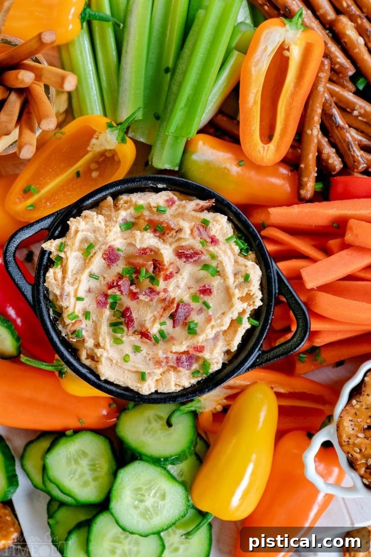 Assortment of dippers like pretzels, vegetables, and breadsticks surrounding a bowl of Beer Cheese Dip