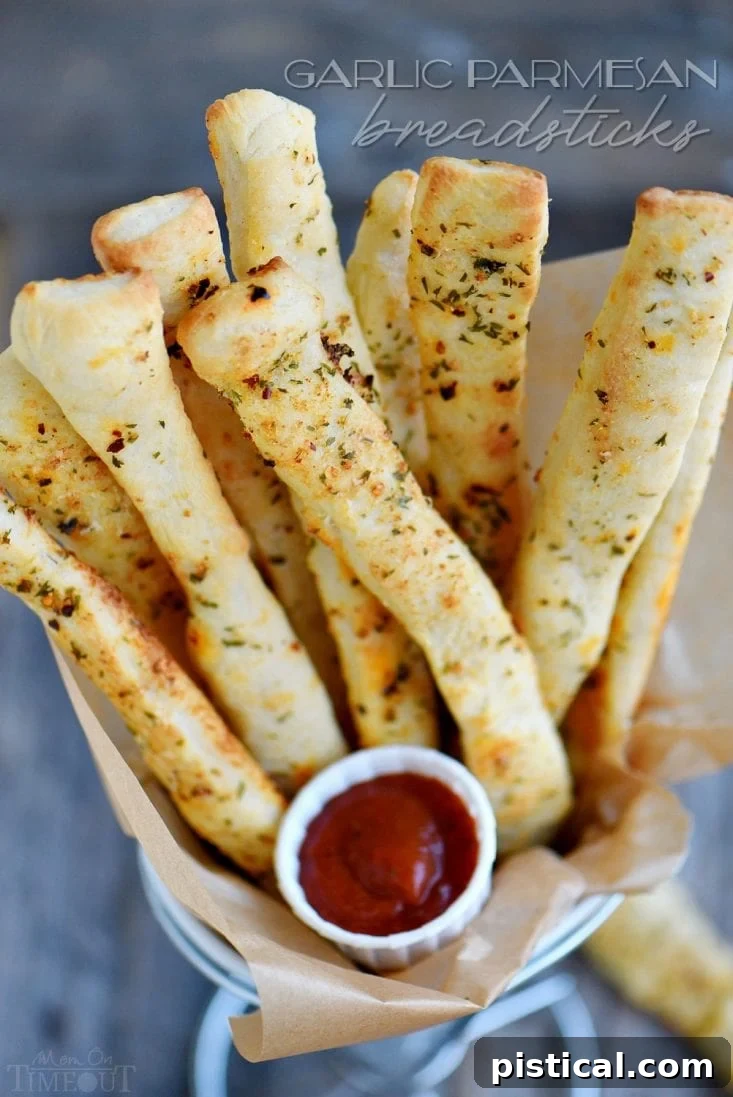 Irresistible Garlic Parmesan Breadsticks: The perfect easy side dish or appetizer for dinner tonight. Loaded with flavor, crispy, and cheesy! Serve with warm marinara and ranch. Delicious Garlic Parmesan Breadsticks with dipping sauce, ready to serve