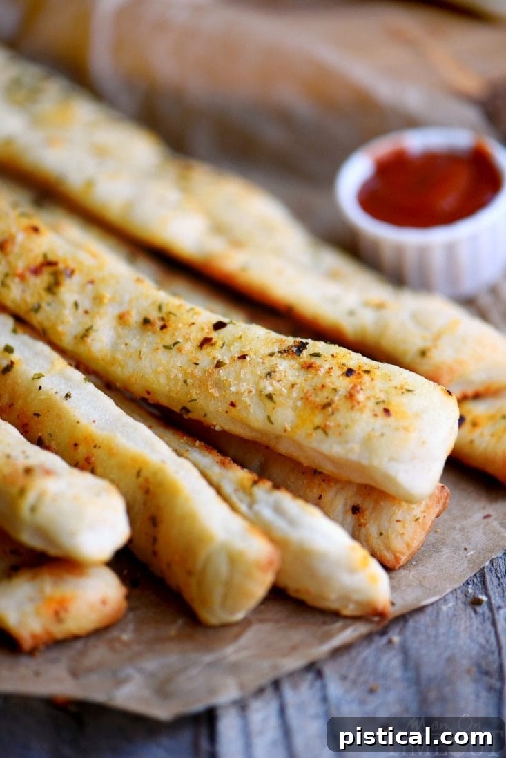 Freshly baked Garlic Parmesan Breadsticks, perfectly golden and aromatic, ready to be served as an appetizer or side. Golden-brown parmesan breadsticks seasoned with herbs and red pepper flakes