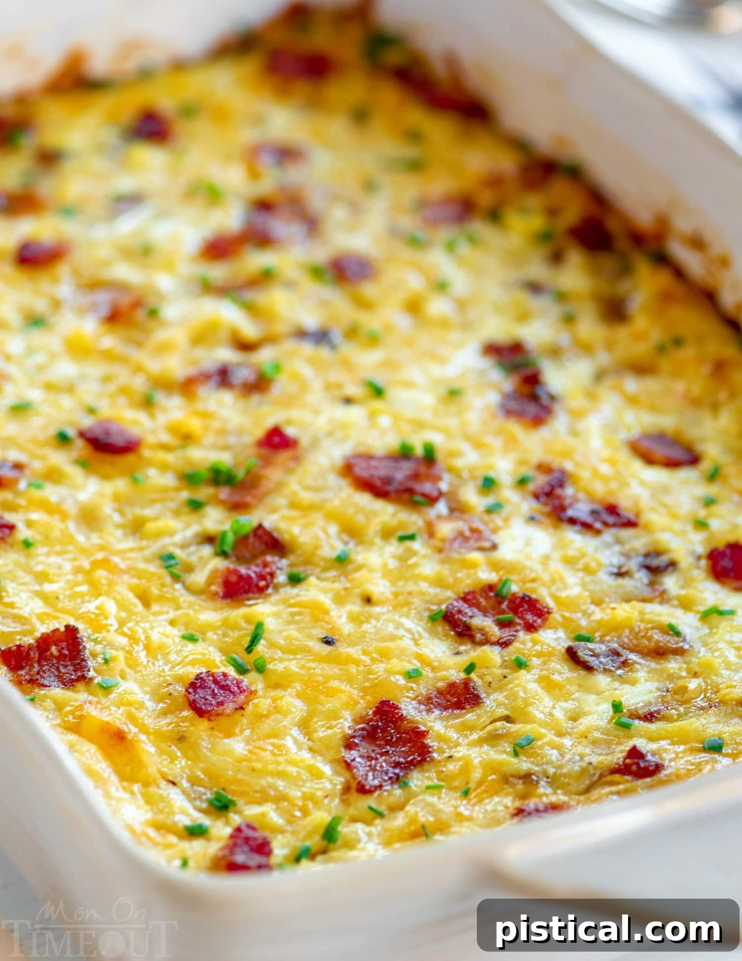 A golden-brown breakfast casserole with bacon and hash browns, cooling in a baking dish.