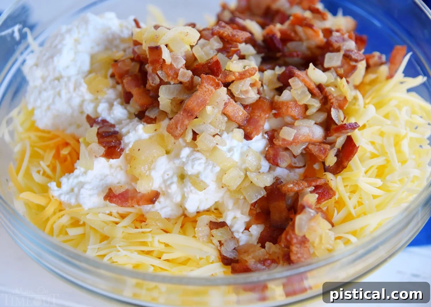 Assorted ingredients for an easy breakfast casserole, including eggs, bacon, hash browns, and cheeses, in a large bowl.