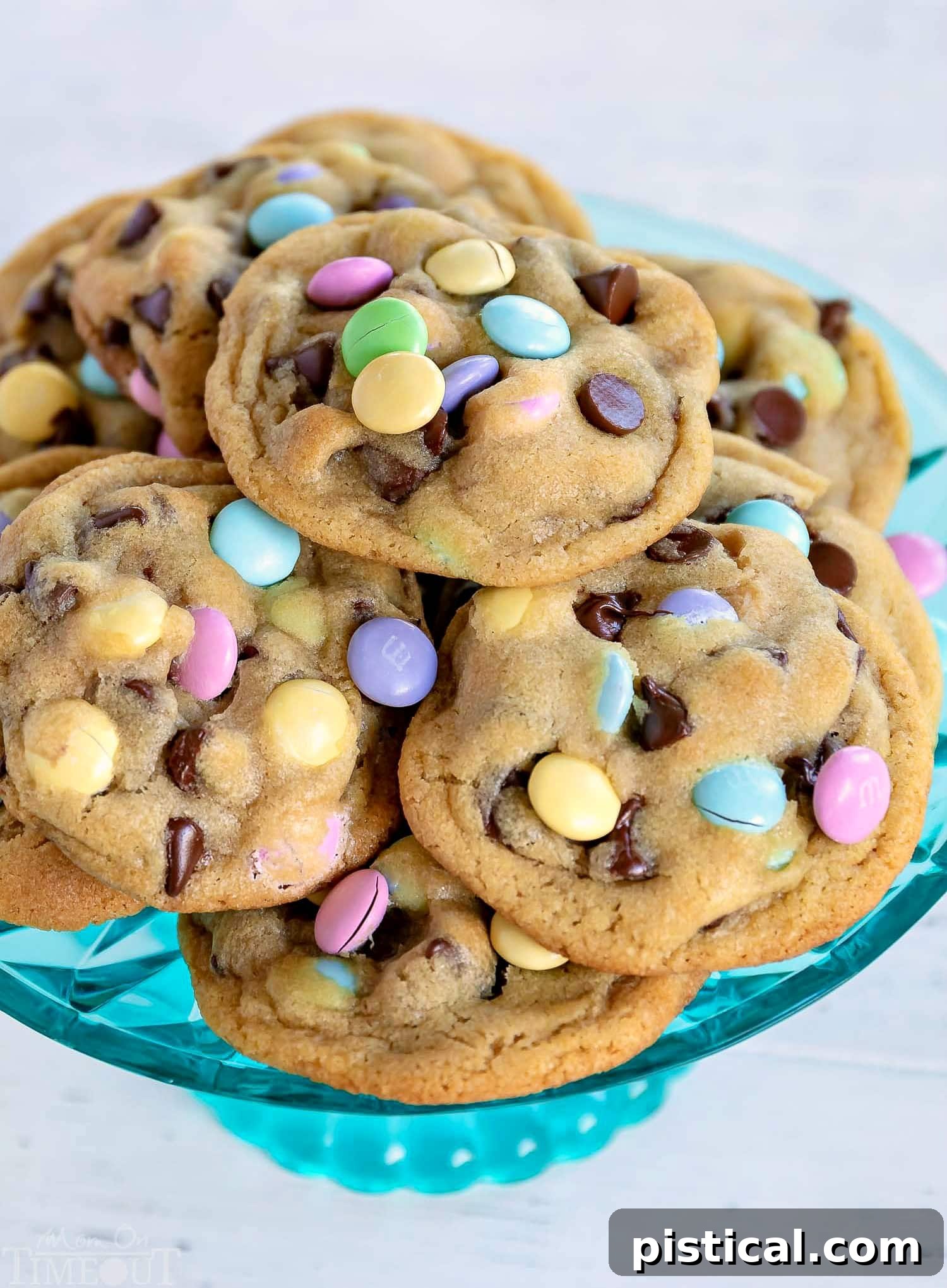 chocolate-chip-cookies-teal-cake-stand - Close-up of thick, soft, and chewy chocolate chip cookies adorned with Easter M&Ms on a teal cake stand.