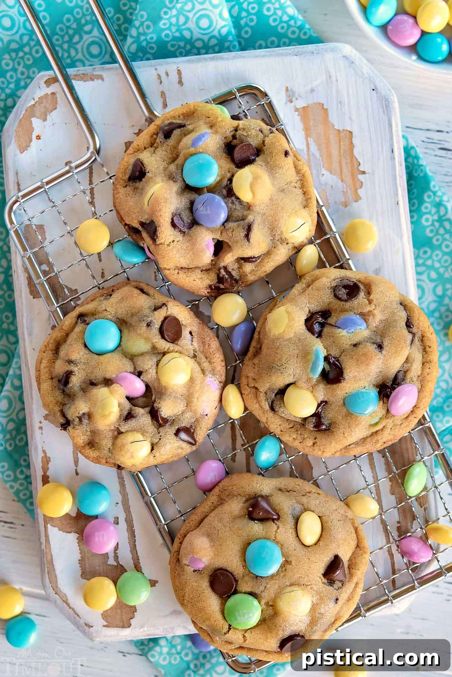 chocolate-chip-cookies-cutting-board - Freshly baked chocolate chip cookies with colorful Easter M&Ms cooling on a wooden cutting board.
