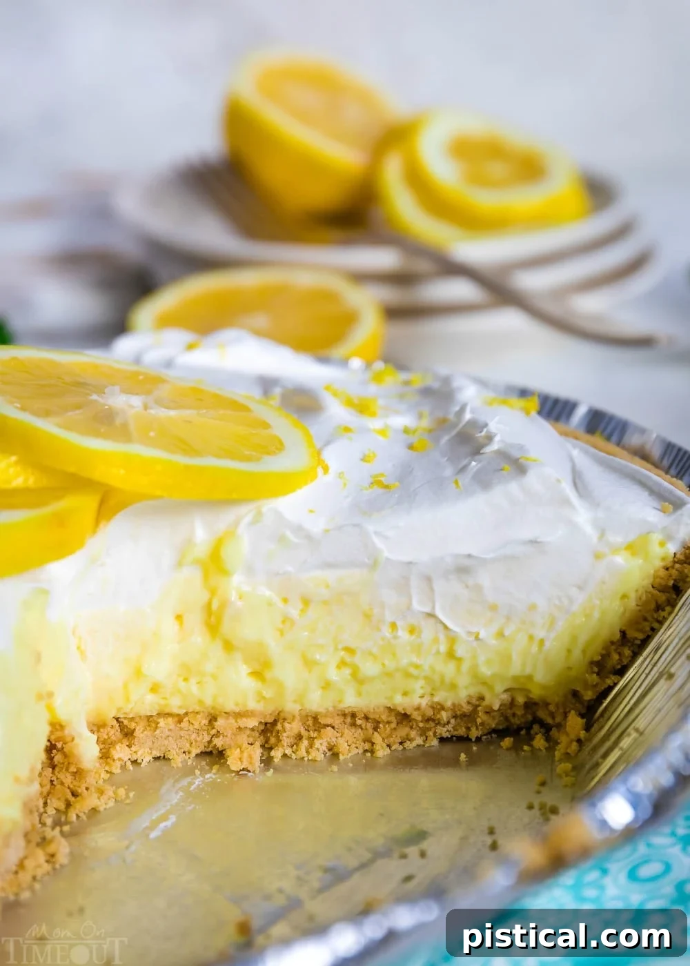 A whole No Bake Lemon Pie in a pie tin with a single slice removed, revealing the creamy lemon filling and graham cracker crust.