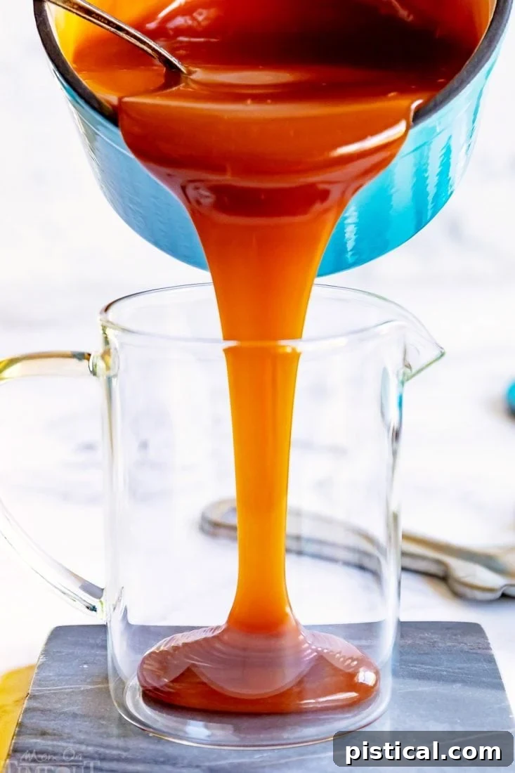 Warm caramel sauce being poured into a glass jar for storage