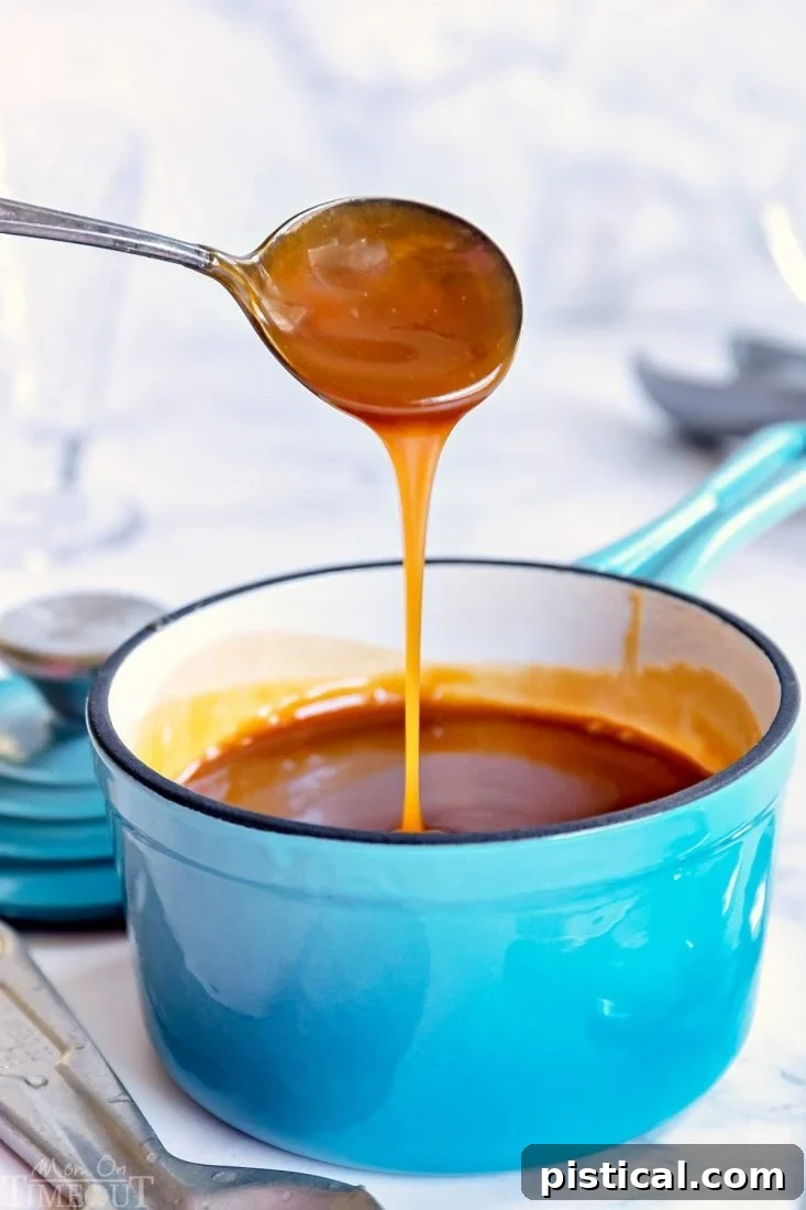 Thick homemade caramel sauce being drizzled from a spoon