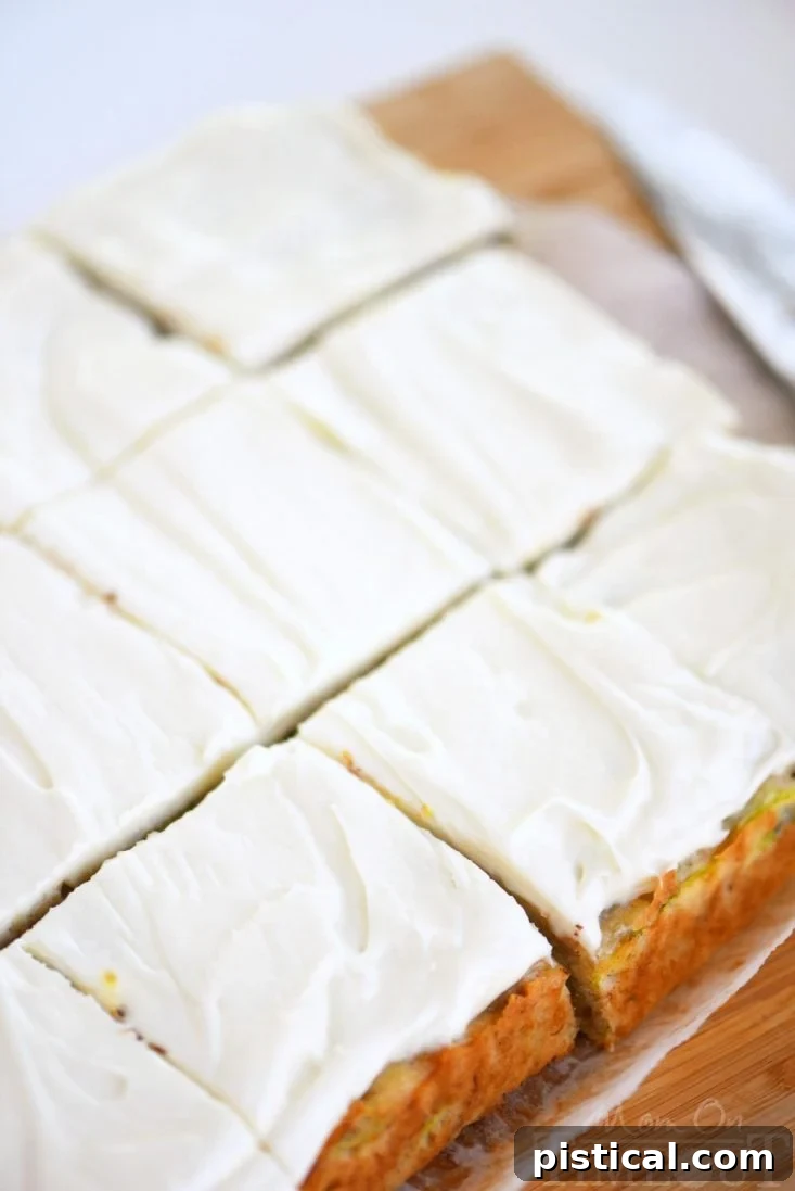 Individual slices of moist Zucchini Banana Cake with cream cheese frosting, presented on a cutting board.