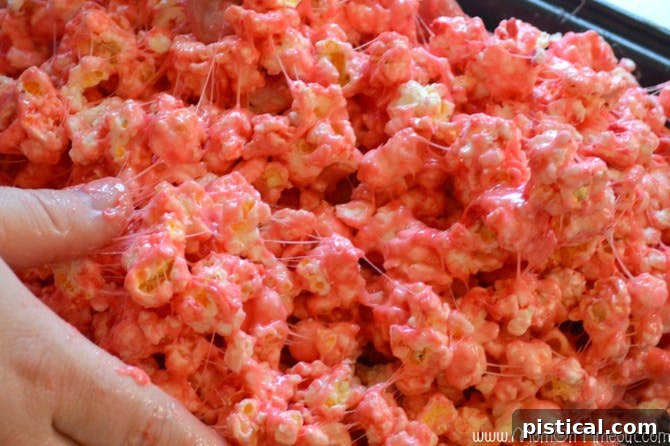 Hands generously buttered, mixing popcorn and marshmallow mixture to form festive balls.