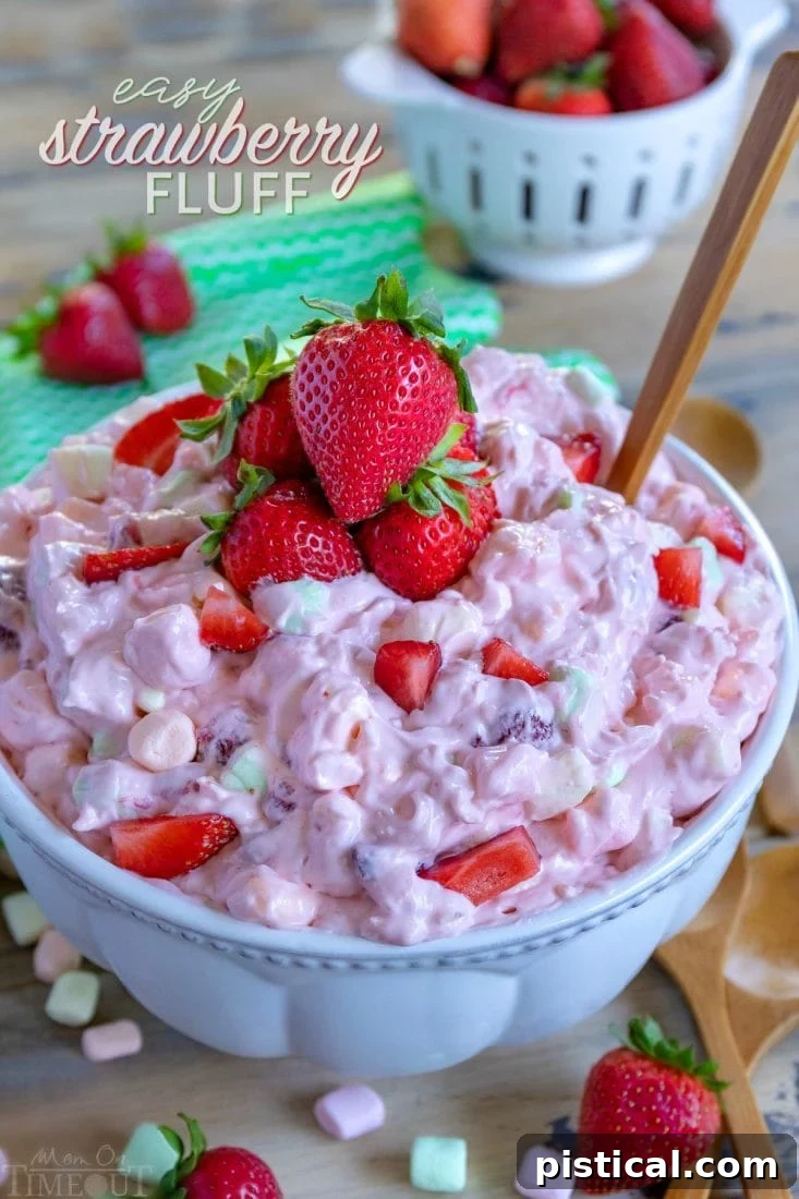 A large bowl of creamy Strawberry Fluff topped with fresh strawberry halves, ready to be served at a gathering.