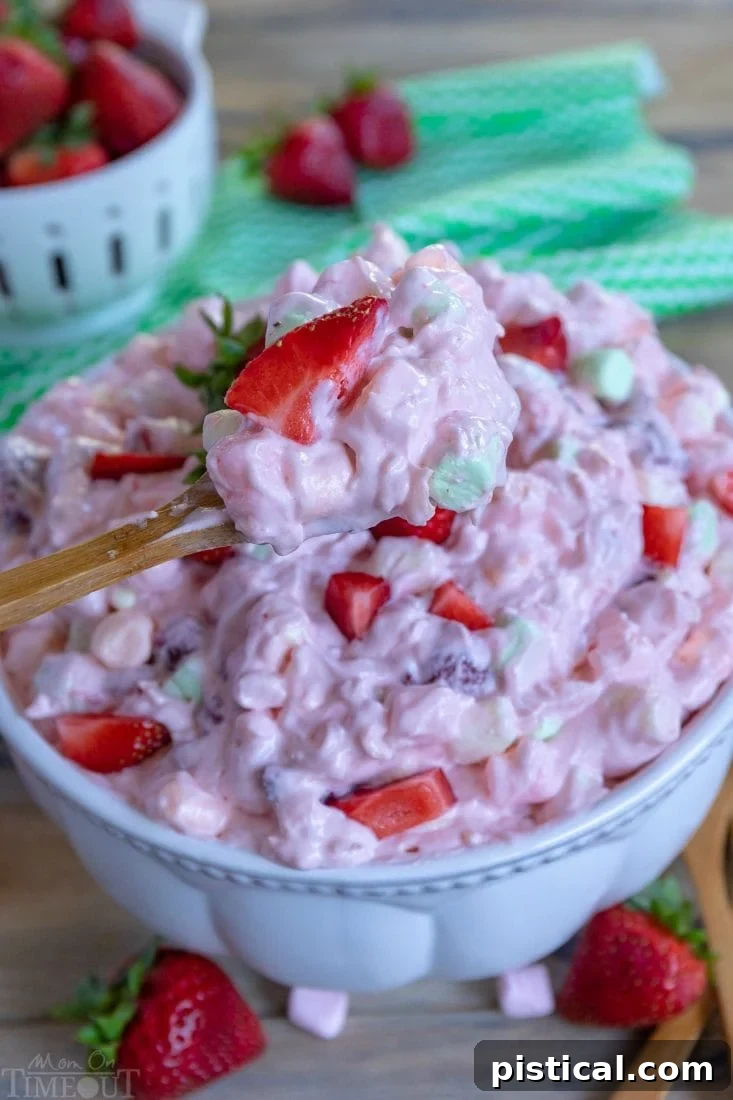 A spoonful of fluffy Strawberry Fluff dessert, showing its creamy texture and bits of strawberry and marshmallow.