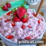 A large bowl of creamy Strawberry Fluff topped with fresh strawberry halves, ready to be served.