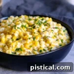 black bowl of creamed corn with chives snipped on top.