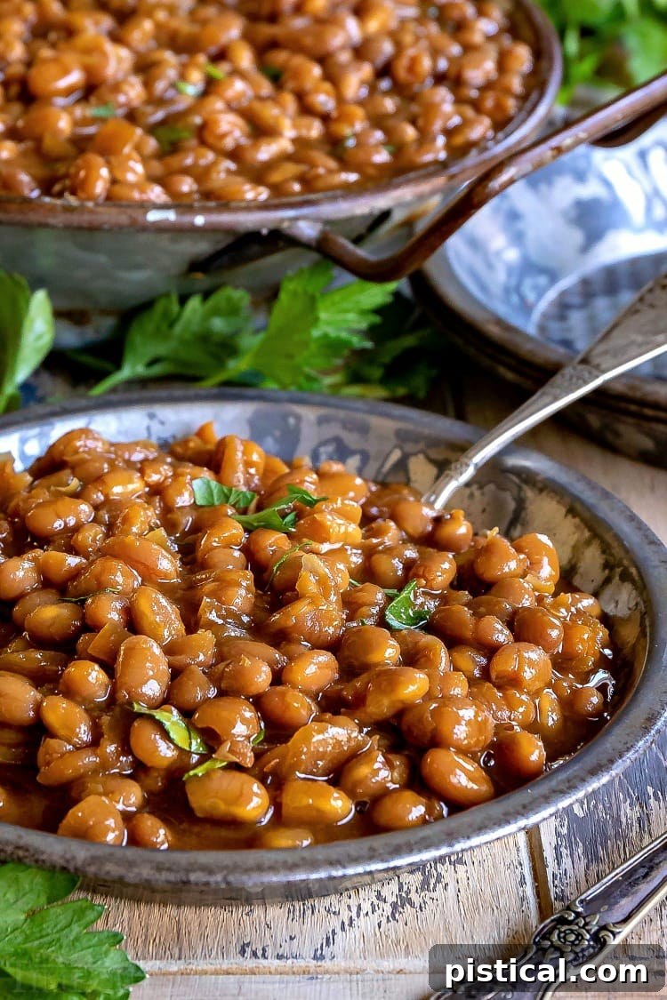 Rich, flavorful homemade baked beans served in an elegant antique silver bowl.