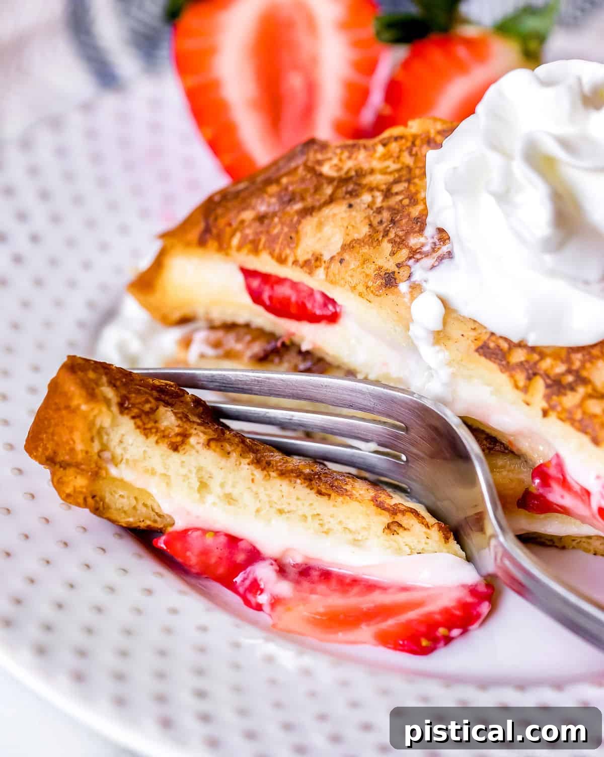 A close-up shot of a bite taken from a piece of Strawberry Cream Cheese Stuffed French Toast, showcasing the rich filling.