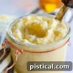 honey butter in jar with knife and extra honey