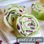 turkey pinwheels recipe with dried cranberries on small white cutting board squared
