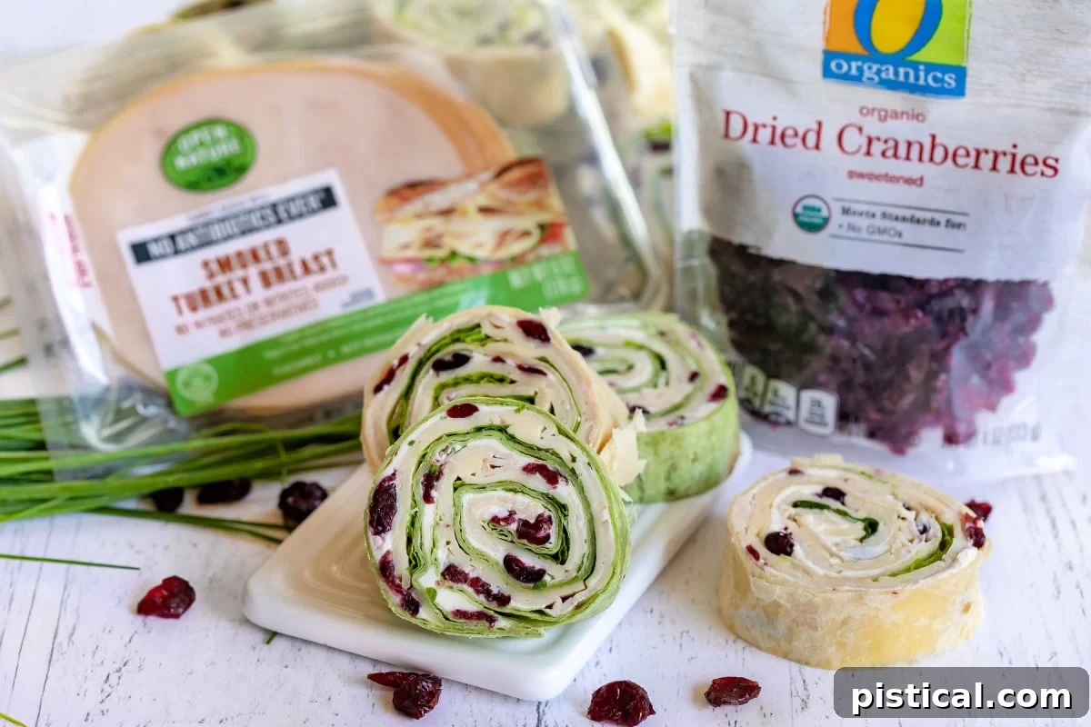 turkey cranberry pinwheels on small white board with packages of turkey meat and dried cranberries on the sides