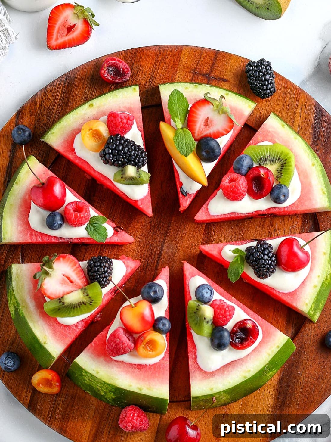 A large, perfectly round watermelon pizza, generously topped with a creamy cream cheese glaze and an assortment of colorful fresh fruits, neatly cut into wedges and arranged on a rustic wooden board.
