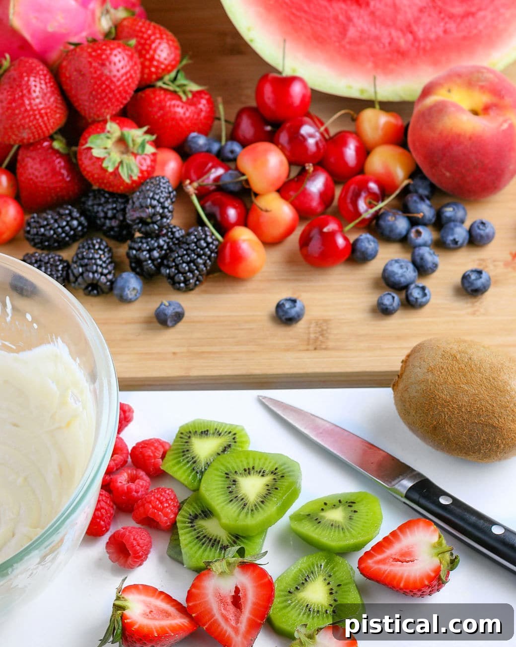 An assortment of fresh fruits, including berries, kiwi, and peaches, beautifully cut and ready to be placed as toppings on a watermelon pizza.