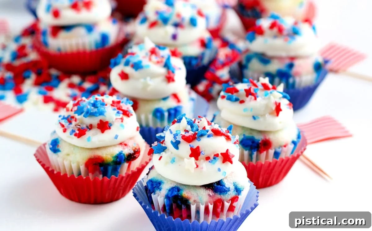 A charming display of mini vanilla cupcakes, artfully decorated with patriotic red, white, and blue sprinkles and icing, ready for a 4th of July celebration.