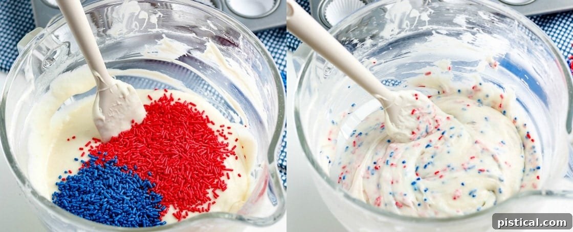 Close-up of fluffy mini vanilla cupcake batter in a mixing bowl, studded with vibrant red and blue jimmie sprinkles, ready for baking.