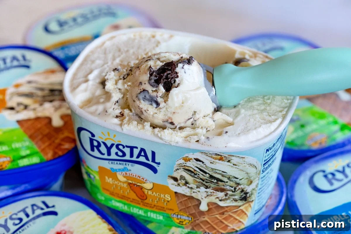 A scoop of rich Moose Tracks ice cream being served from a container, showing the swirls of chocolate and peanut butter throughout.