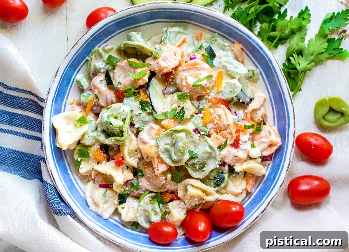Creamy Tortellini Pasta Salad in a white and blue bowl, garnished with fresh herbs and Parmesan.