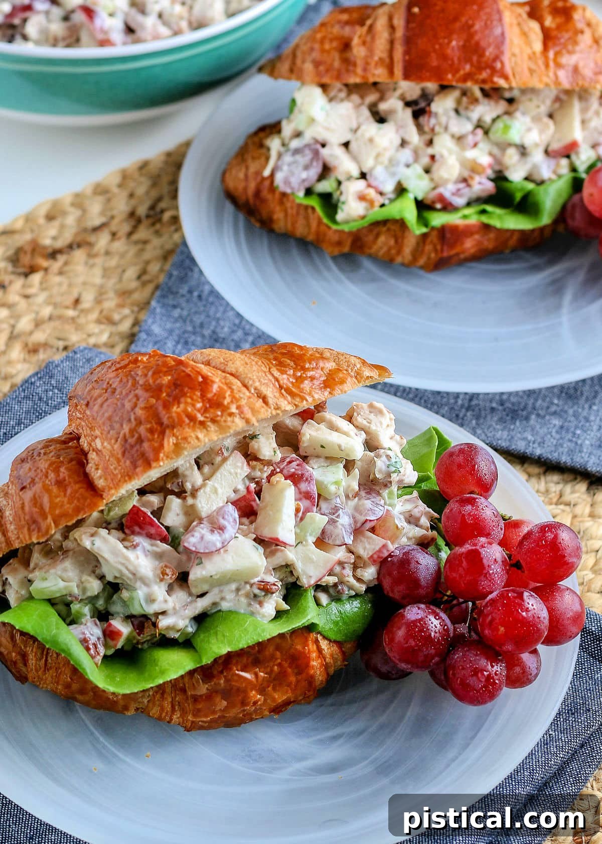 2 chicken salad sandwiches on white plates with blue napkins
