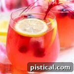Berry Lemonade in a wine glass garnished with lemon slices