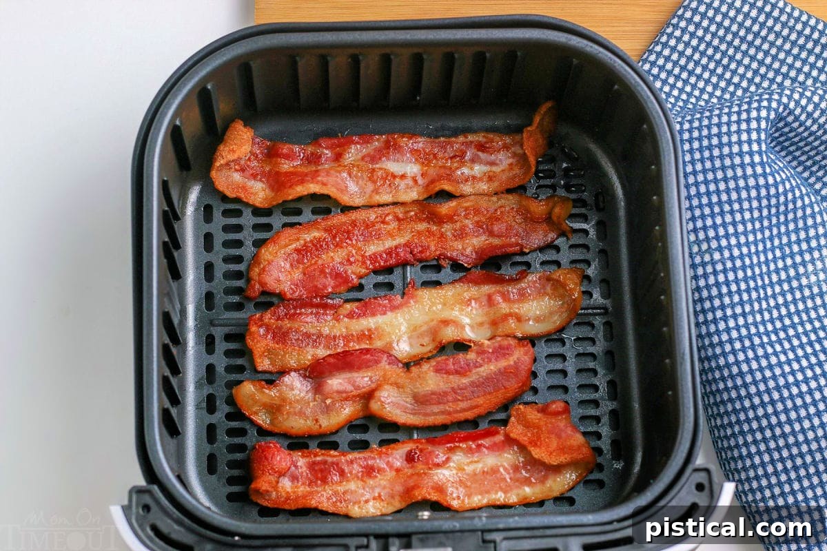 Cooked, crispy bacon strips arranged neatly in an air fryer basket.