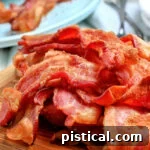 air fryer bacon piled high on wood board with blue plate in the background square