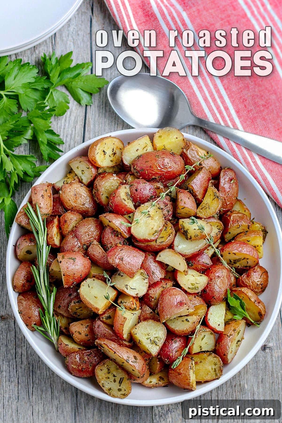 white plate with roasted potatoes garnished with fresh herbs and red towel in the upper right corner white text overlay