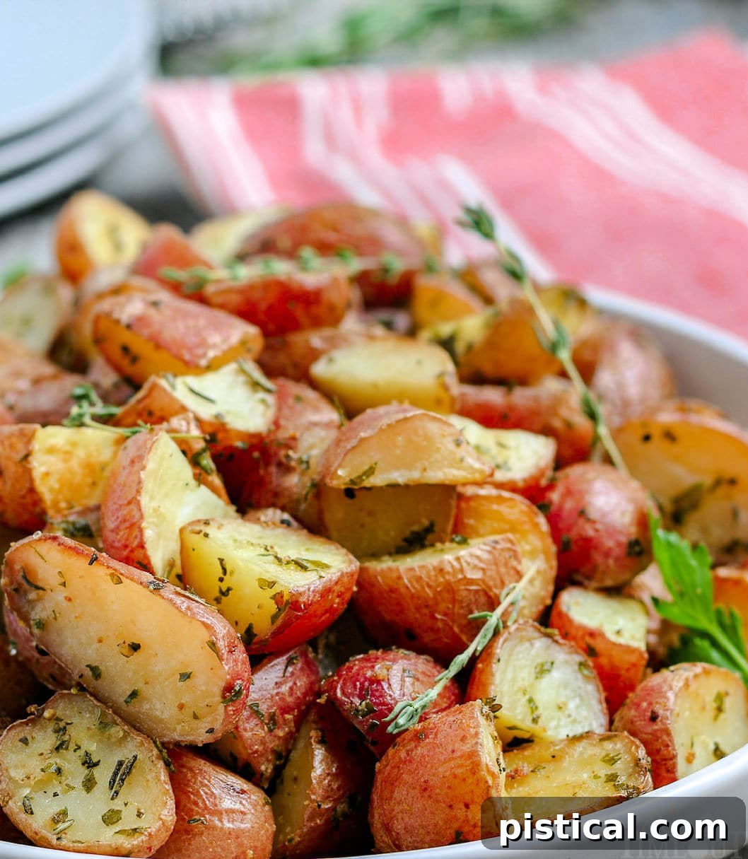 roasted potatoes recipe close up in white bowl with stack of plates in background