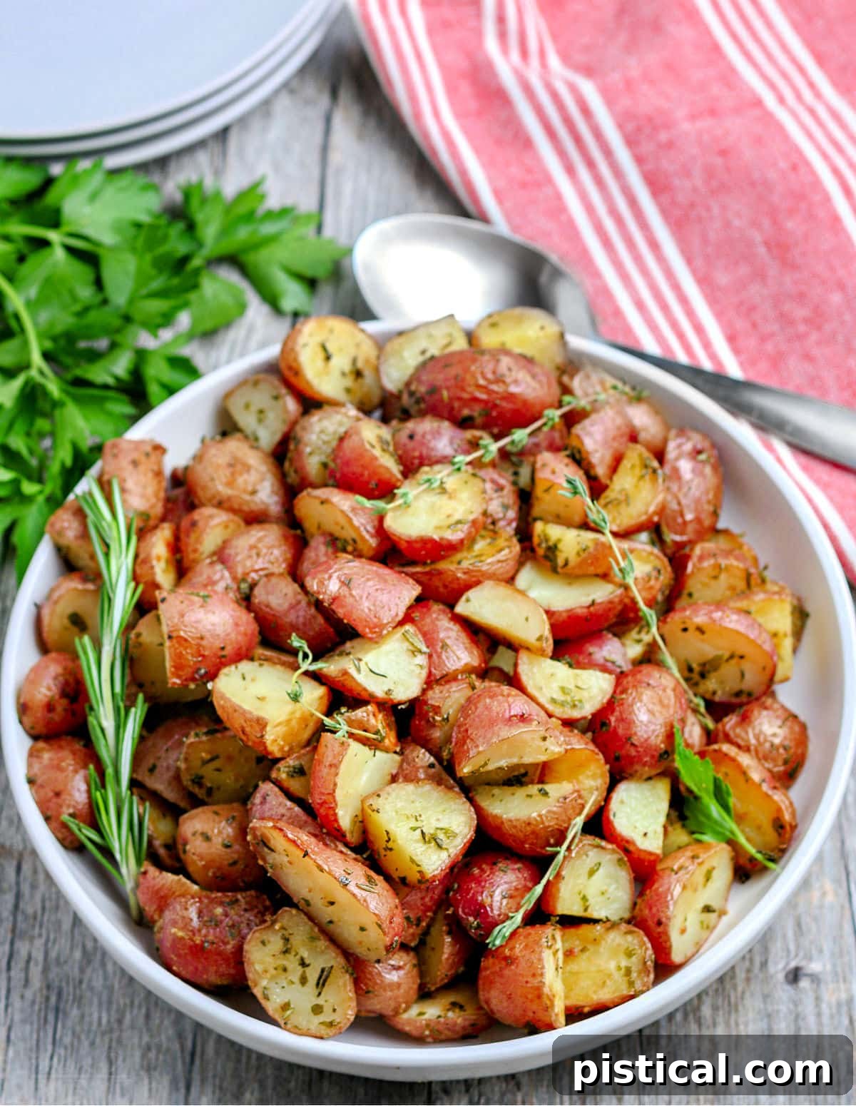 roasted red potatoes on white plate sitting on red and white striped towel
