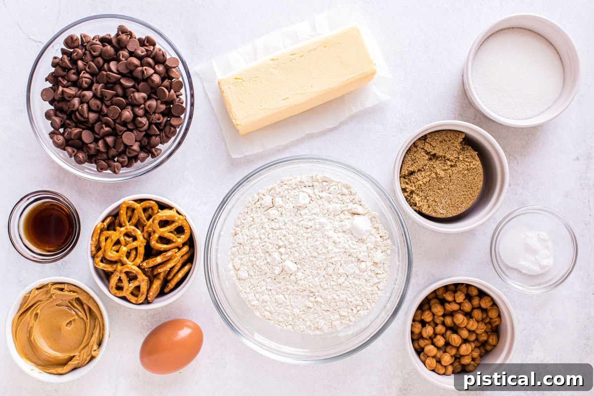 Measured out pretzel peanut butter chocolate chip cookie ingredients arranged in small bowls on a clean white surface.