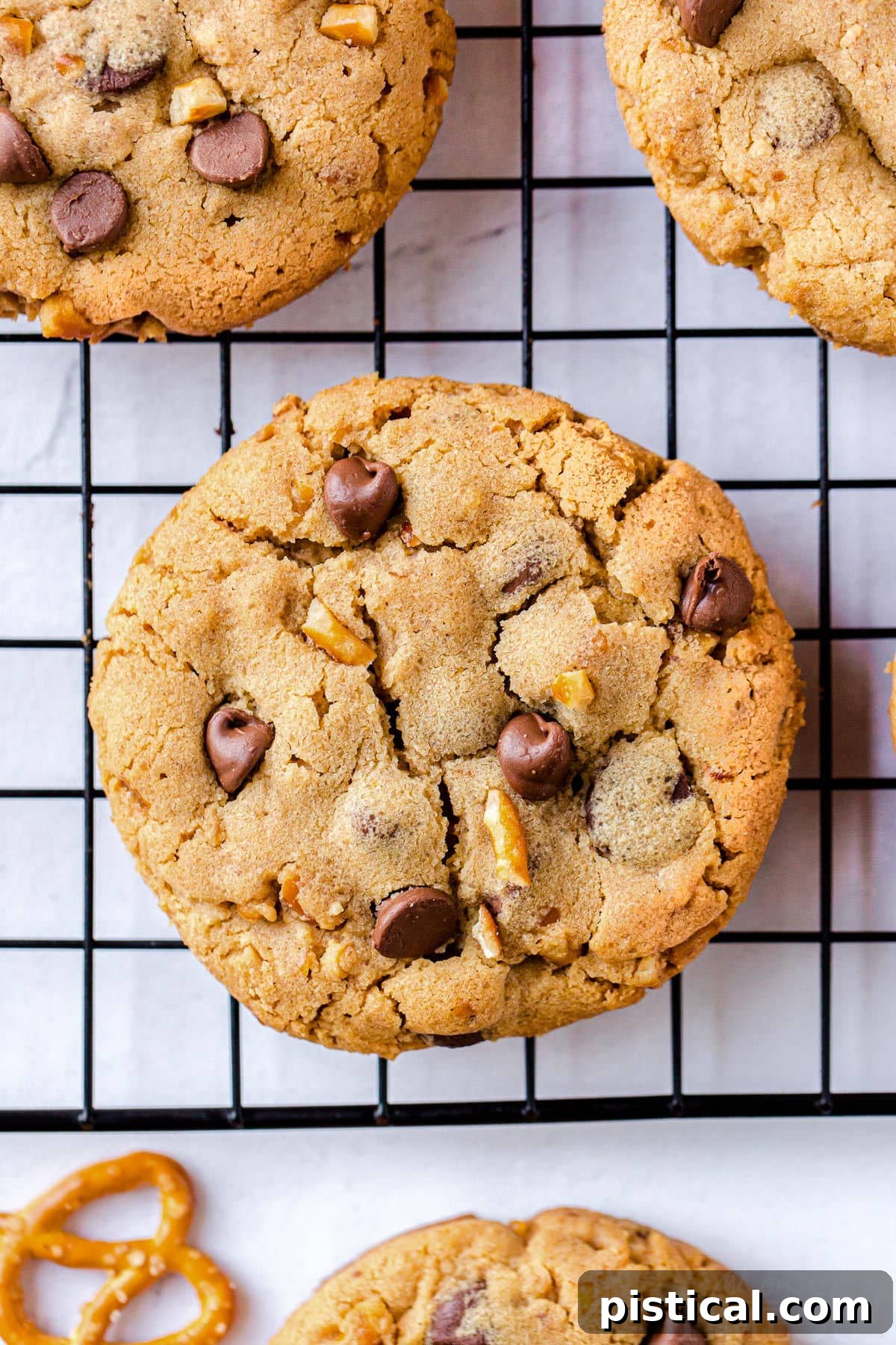 A top-down view of a freshly baked cookie resting on a black cooling wire rack.